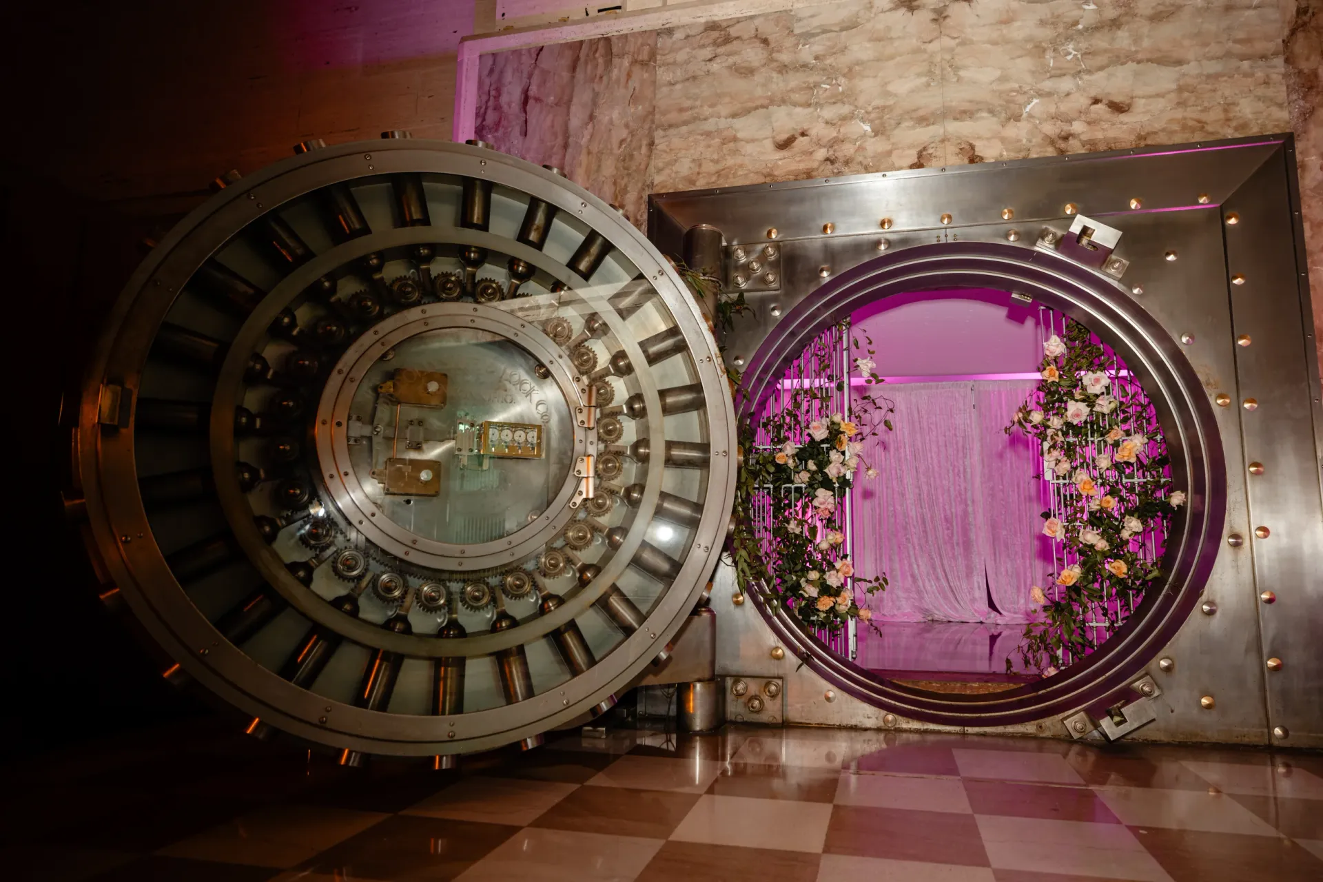 Historic bank vault doorway adorned with flowers and warm lighting leading into a lavish celebration space