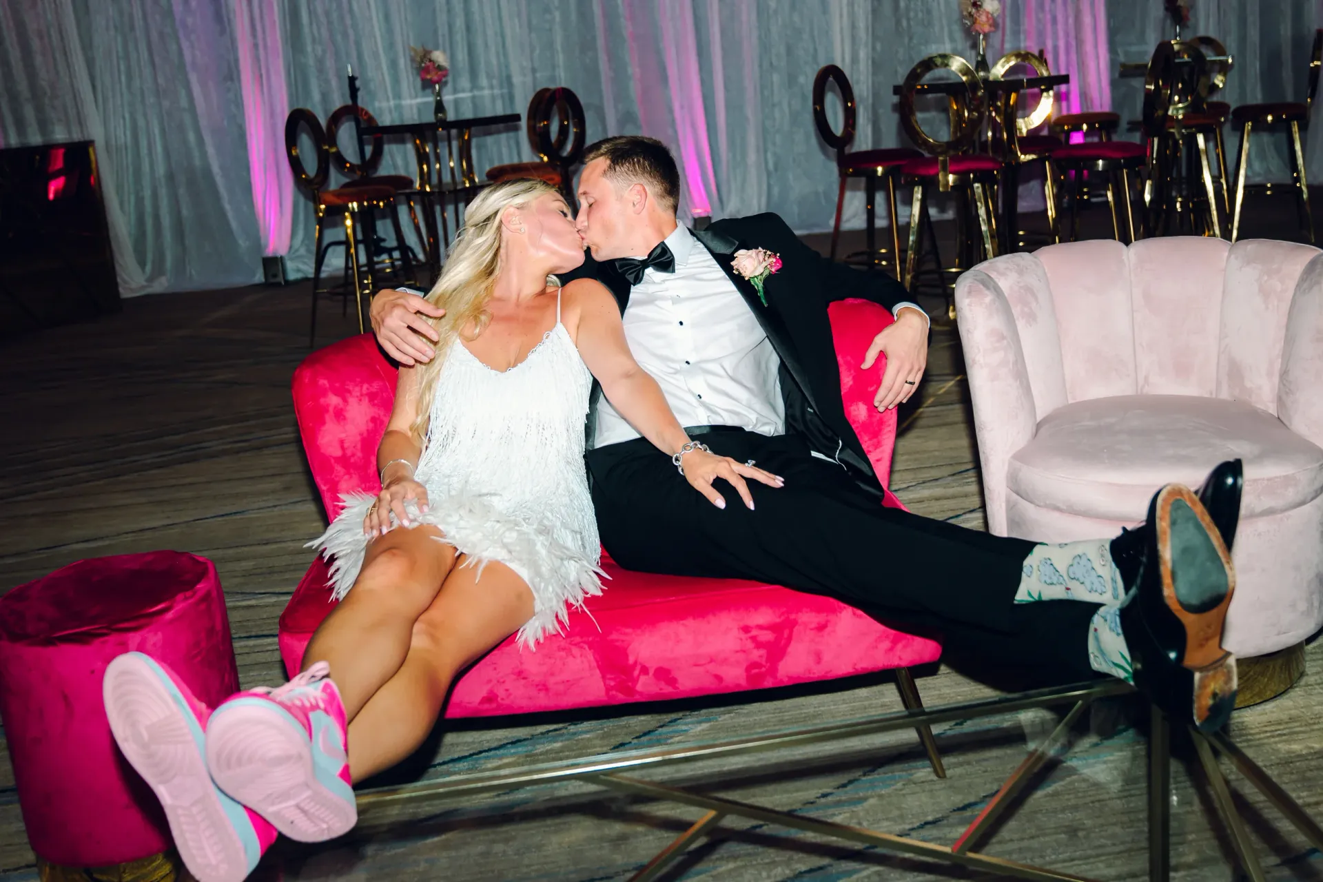 Bride and groom celebrating together on a pink velvet couch