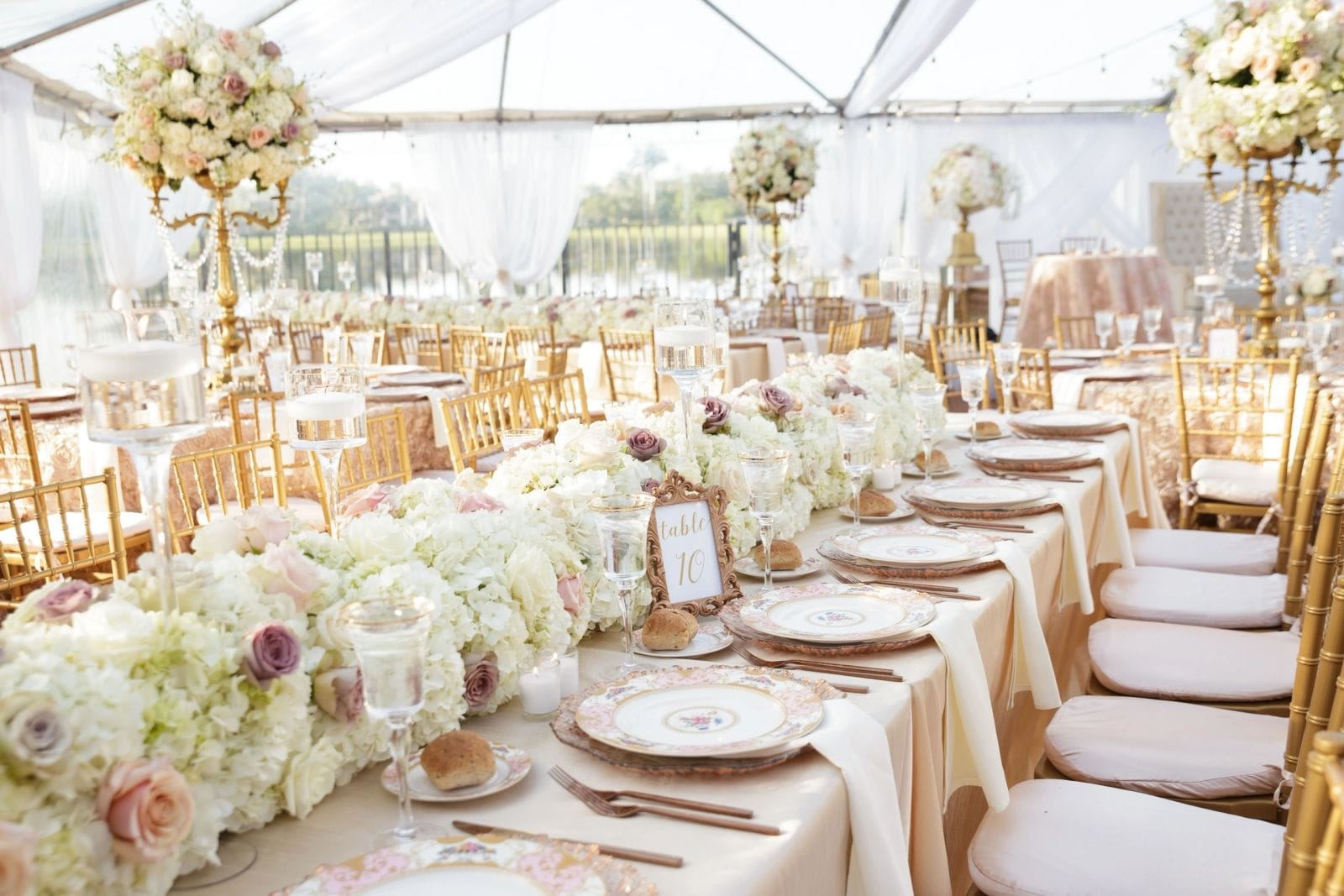 One long banquet table set under a clear tent with candles and low florals