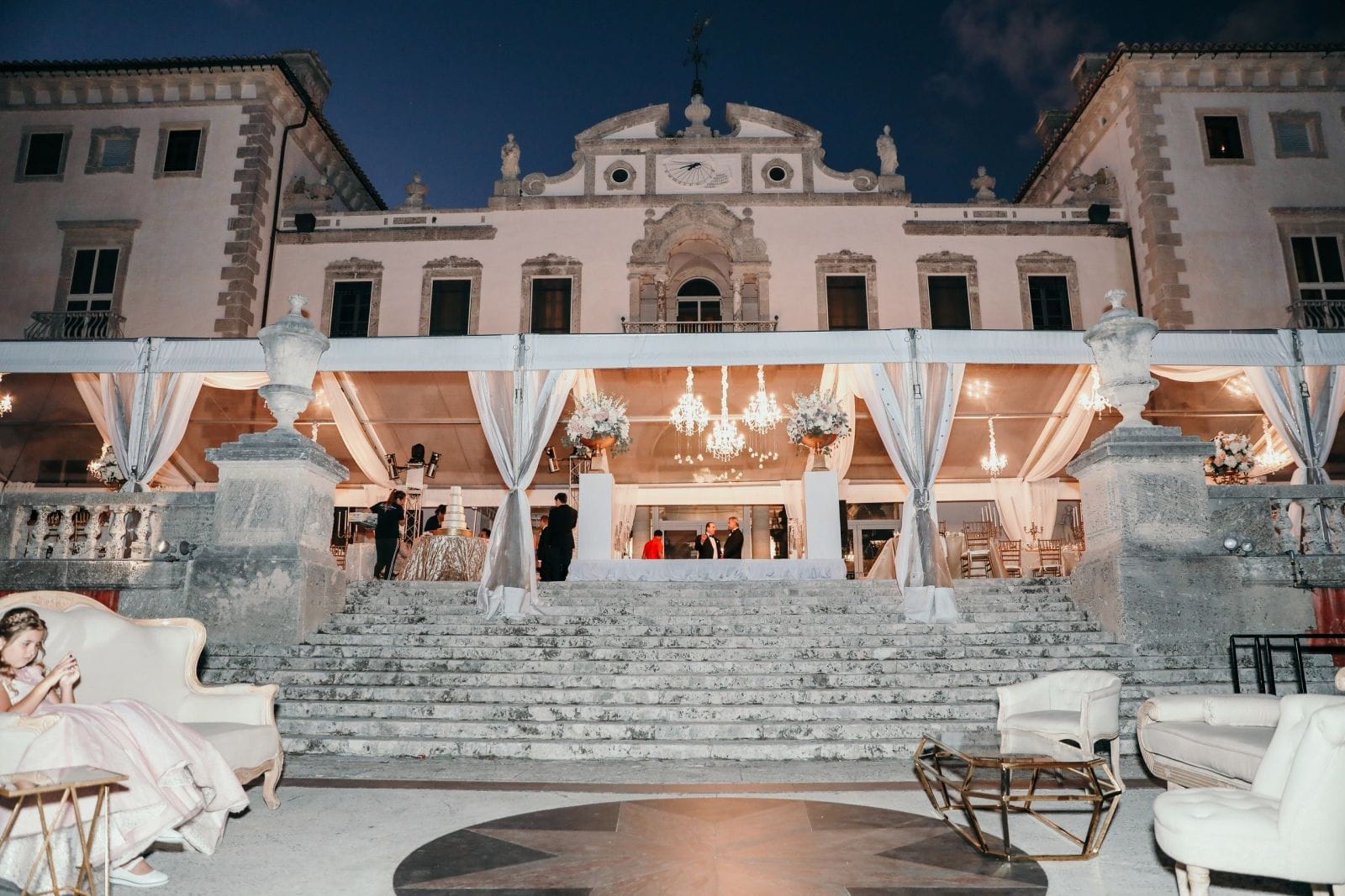 The historic Vizcaya villa lit at night with a draped entry and florals